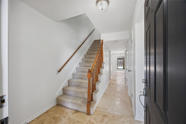foyer featuring stairs and baseboards