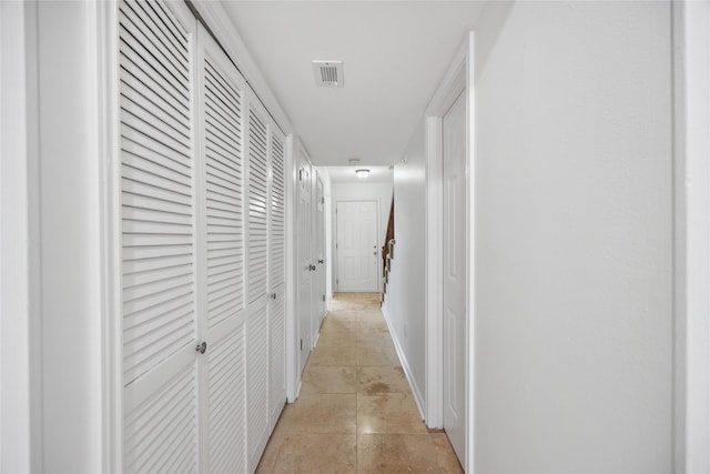 corridor with light tile patterned floors and baseboards