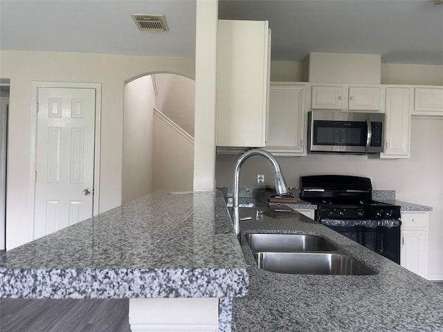 5918 Fergis Dr, Katy, TX 77449 - kitchen with stainless steel microwave, black range with gas stovetop, white cabinetry, and dark stone counters
