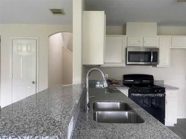 5918 Fergis Dr, Katy, TX 77449 - kitchen with stainless steel microwave, black range with gas stovetop, a sink, and dark stone counters