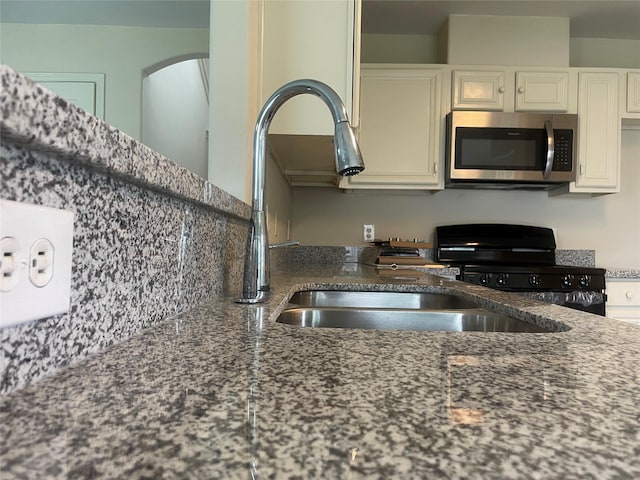 5918 Fergis Dr, Katy, TX 77449 - kitchen featuring stainless steel microwave, stove, dark stone countertops, white cabinetry, and a sink