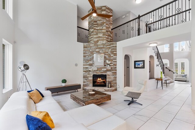 6203 Aspen Pass Dr, Kingwood, TX 77345 - living room featuring a towering ceiling, arched walkways, a stone fireplace, stairs, and a ceiling fan