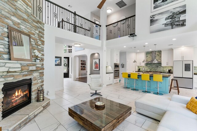 6203 Aspen Pass Dr, Kingwood, TX 77345 - living room featuring arched walkways, light marble finish flooring, a stone fireplace, baseboards, and a towering ceiling
