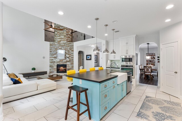6203 Aspen Pass Dr, Kingwood, TX 77345 - kitchen with arched walkways, a sink, appliances with stainless steel finishes, light marble finish floors, and blue cabinetry