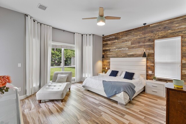 6203 Aspen Pass Dr, Kingwood, TX 77345 - bedroom with wooden walls, light wood finished floors, an accent wall, and ceiling fan