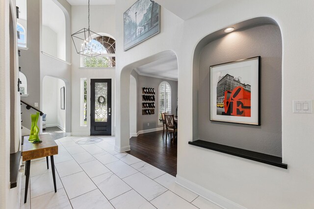 6203 Aspen Pass Dr, Kingwood, TX 77345 - foyer featuring a chandelier, arched walkways, baseboards, marble look tile flooring, and a towering ceiling