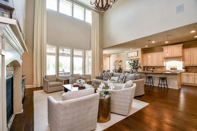 28011 Burnett Hills Ln, Fulshear, TX 77441 - living room with a towering ceiling, dark wood-style floors, a glass covered fireplace, a chandelier, and ceiling fan