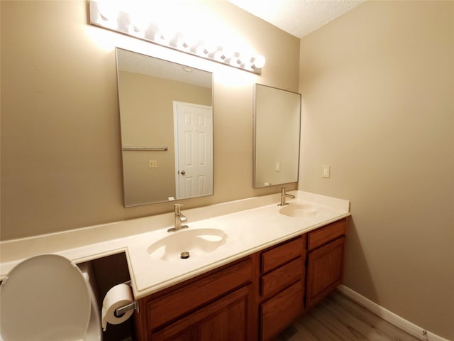 3226 Country Club Blvd, Stafford, TX 77477 - bathroom with double vanity, wood finished floors, a textured ceiling, and baseboards