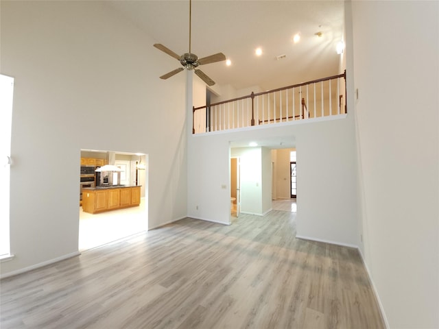 3226 Country Club Blvd, Stafford, TX 77477 - unfurnished living room with high vaulted ceiling, light wood-style floors, a ceiling fan, and baseboards