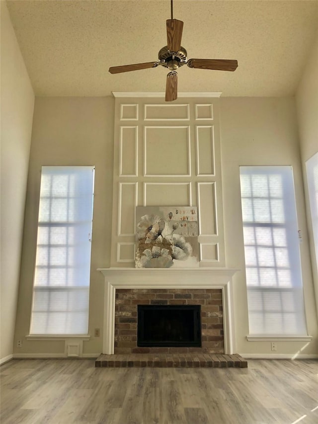 3226 Country Club Blvd, Stafford, TX 77477 - unfurnished living room featuring wood finished floors, a textured ceiling, a fireplace, a ceiling fan, and baseboards