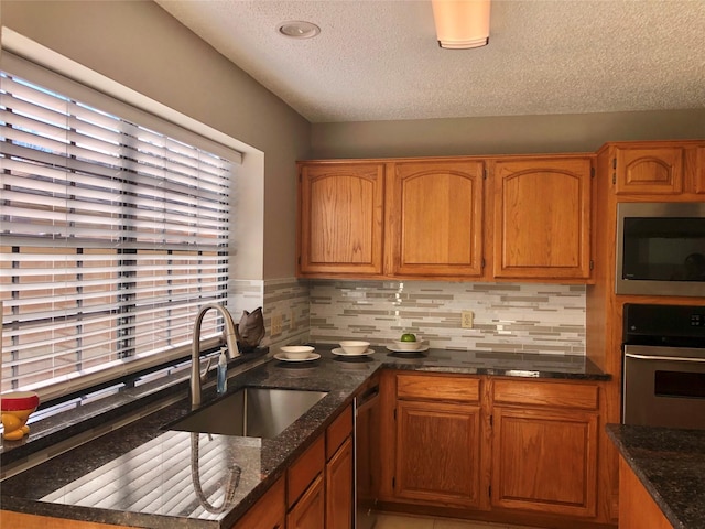 3226 Country Club Blvd, Stafford, TX 77477 - kitchen with appliances with stainless steel finishes, a sink, a textured ceiling, tasteful backsplash, and brown cabinets