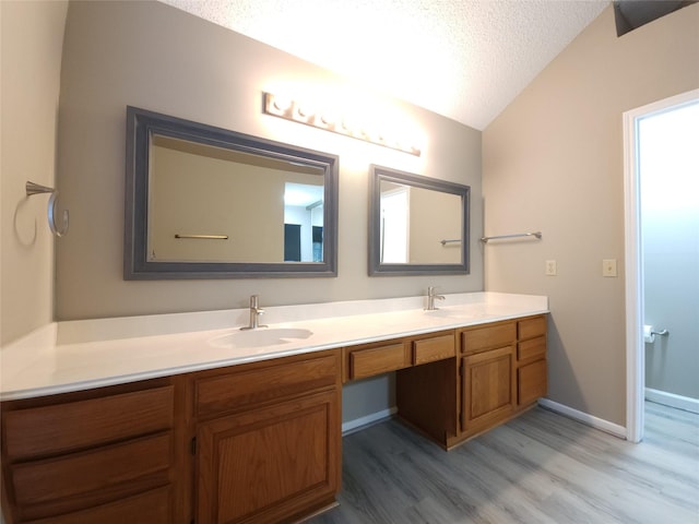 3226 Country Club Blvd, Stafford, TX 77477 - bathroom featuring wood finished floors, vaulted ceiling, double vanity, a textured ceiling, and baseboards