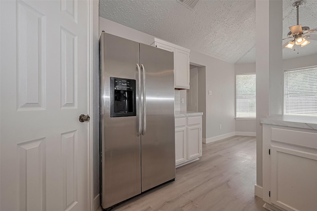 22010 Rivermead Dr, Katy, TX 77449 - kitchen with stainless steel fridge, a textured ceiling, a ceiling fan, white cabinets, and light wood-style flooring