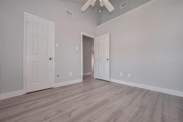 22010 Rivermead Dr, Katy, TX 77449 - unfurnished bedroom with light wood-style flooring, baseboards, ceiling fan, and a towering ceiling