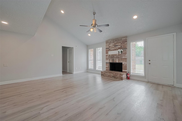 22010 Rivermead Dr, Katy, TX 77449 - unfurnished living room with a ceiling fan, light wood-type flooring, a textured ceiling, baseboards, and a brick fireplace