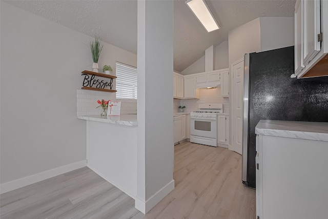 22010 Rivermead Dr, Katy, TX 77449 - kitchen with white range with gas stovetop, freestanding refrigerator, light wood-style flooring, light countertops, and lofted ceiling