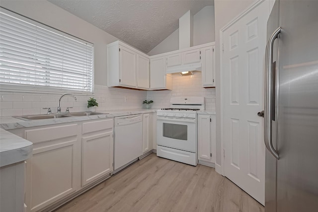 22010 Rivermead Dr, Katy, TX 77449 - kitchen with white appliances, a sink, tasteful backsplash, under cabinet range hood, and vaulted ceiling