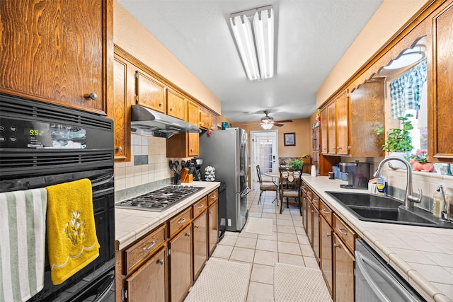 11855 23rd St, Santa Fe, TX 77510 - kitchen featuring tile countertops, stainless steel appliances, a sink, under cabinet range hood, and tasteful backsplash