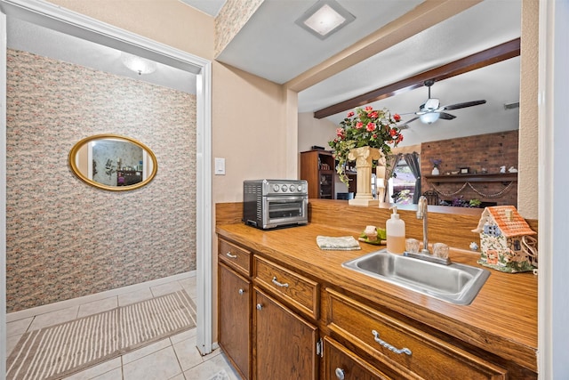 11855 23rd St, Santa Fe, TX 77510 - kitchen with light tile patterned flooring, ceiling fan, beamed ceiling, and brown cabinetry