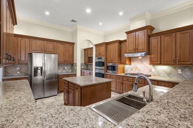 226 Beasley Reef Dr, Beach City, TX 77523 - kitchen featuring stainless steel appliances, a sink, decorative backsplash, light stone countertops, and brown cabinets