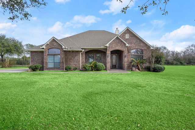 226 Beasley Reef Dr, Beach City, TX 77523 - view of front of property with brick siding, a front lawn, a chimney, and a shingled roof