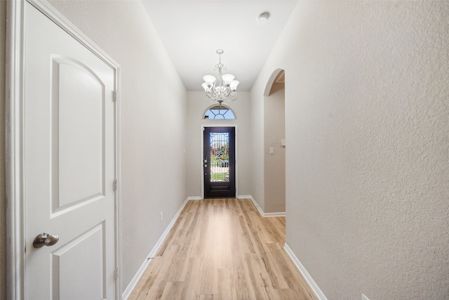 20511 Kendall Cliff Ct, Katy, TX 77449 - doorway to outside featuring arched walkways, light wood-style floors, a chandelier, baseboards, and a textured wall