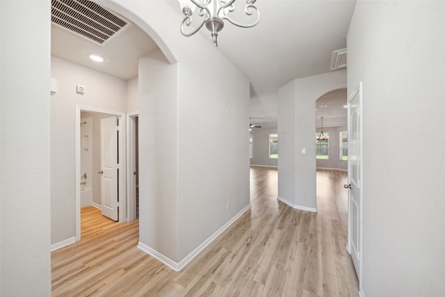 20511 Kendall Cliff Ct, Katy, TX 77449 - corridor featuring a chandelier, arched walkways, light wood finished floors, baseboards, and recessed lighting