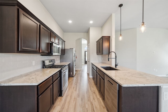 20511 Kendall Cliff Ct, Katy, TX 77449 - kitchen with appliances with stainless steel finishes, a sink, dark brown cabinets, arched walkways, and recessed lighting