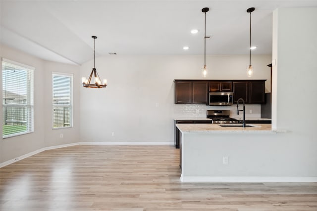 20511 Kendall Cliff Ct, Katy, TX 77449 - kitchen with stainless steel appliances, a sink, a chandelier, light wood-style flooring, and tasteful backsplash