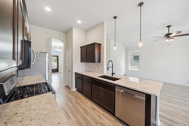 20511 Kendall Cliff Ct, Katy, TX 77449 - kitchen with appliances with stainless steel finishes, a sink, dark brown cabinetry, arched walkways, and light wood-style floors