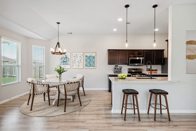 20511 Kendall Cliff Ct, Katy, TX 77449 - kitchen with appliances with stainless steel finishes, a sink, a chandelier, tasteful backsplash, and dark brown cabinetry