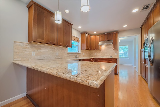 5243 Stillbrooke Dr, Houston, TX 77096 - kitchen featuring under cabinet range hood, a peninsula, plenty of natural light, freestanding refrigerator, and recessed lighting