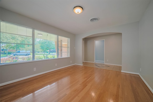 5243 Stillbrooke Dr, Houston, TX 77096 - empty room featuring arched walkways, baseboards, and light wood-style floors