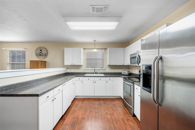 189 New Cove Dr, Livingston, TX 77351 - kitchen featuring appliances with stainless steel finishes, a sink, dark countertops, and a peninsula