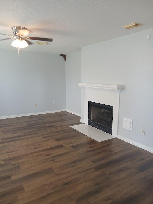 13523 La Concha Ln, Houston, TX 77083 - unfurnished living room with a fireplace with flush hearth, a ceiling fan, dark wood-style floors, and baseboards