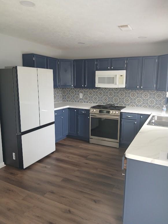 13523 La Concha Ln, Houston, TX 77083 - kitchen with white appliances, light countertops, a sink, dark wood-style flooring, and tasteful backsplash