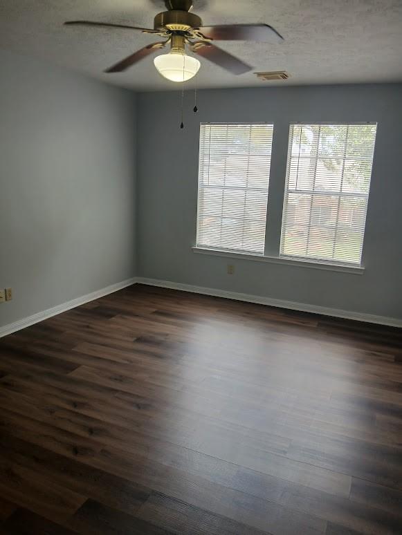 13523 La Concha Ln, Houston, TX 77083 - empty room featuring dark wood-type flooring, baseboards, ceiling fan, and a textured ceiling