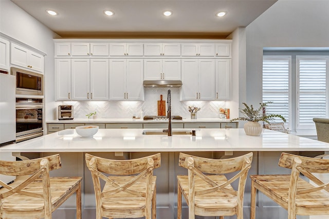 24910 Hibiscus Garden Way, Katy, TX 77493 - kitchen with oven, backsplash, white cabinets, built in microwave, and recessed lighting
