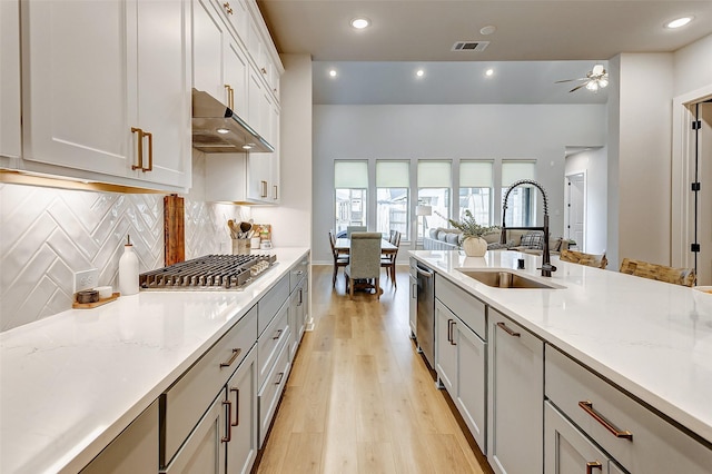 24910 Hibiscus Garden Way, Katy, TX 77493 - kitchen with a sink, under cabinet range hood, appliances with stainless steel finishes, light wood finished floors, and recessed lighting