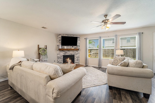 16731 Foursquare Dr, Conroe, TX 77385 - living room featuring ceiling fan, a fireplace, dark wood-style flooring, baseboards, and a textured ceiling