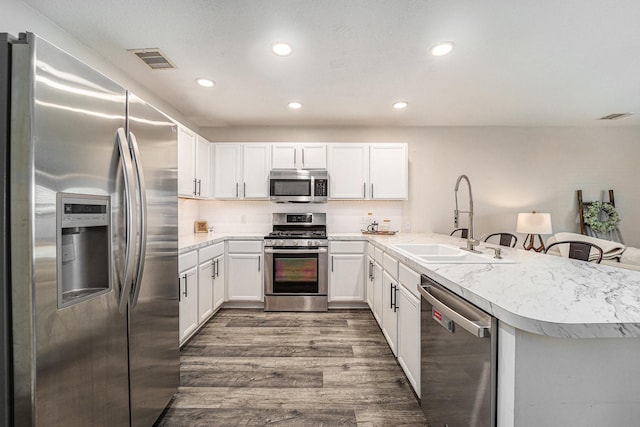 16731 Foursquare Dr, Conroe, TX 77385 - kitchen with appliances with stainless steel finishes, a sink, a peninsula, dark wood-type flooring, and light countertops
