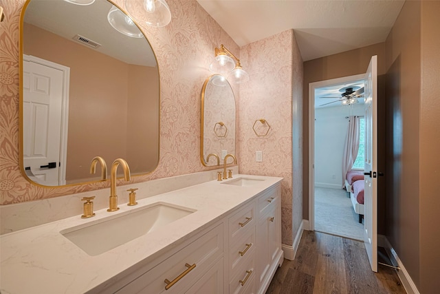 8113 Tranquil Lake Way, Conroe, TX 77385 - ensuite bathroom with wood finished floors, double vanity, wallpapered walls, ceiling fan, and baseboards