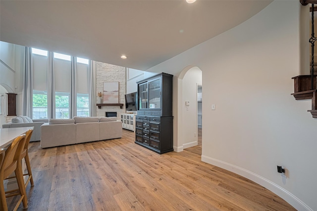 8113 Tranquil Lake Way, Conroe, TX 77385 - living area with a fireplace, arched walkways, light wood-style floors, baseboards, and recessed lighting