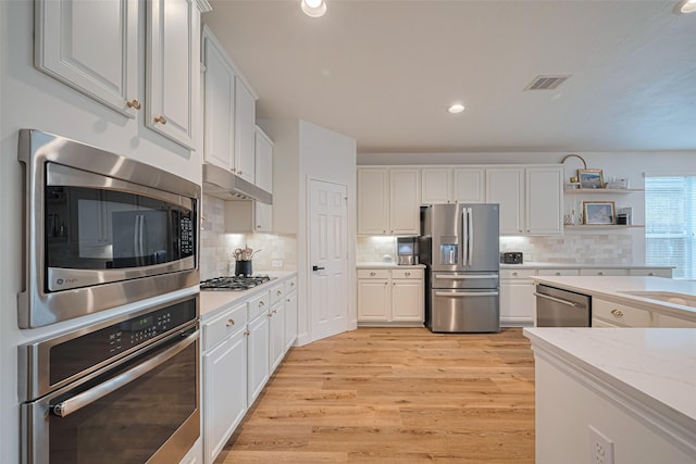 8113 Tranquil Lake Way, Conroe, TX 77385 - kitchen featuring stainless steel appliances, white cabinetry, light wood-style floors, backsplash, and recessed lighting