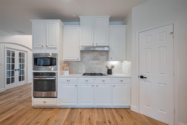 8113 Tranquil Lake Way, Conroe, TX 77385 - kitchen featuring stainless steel appliances, under cabinet range hood, light wood-type flooring, light countertops, and tasteful backsplash