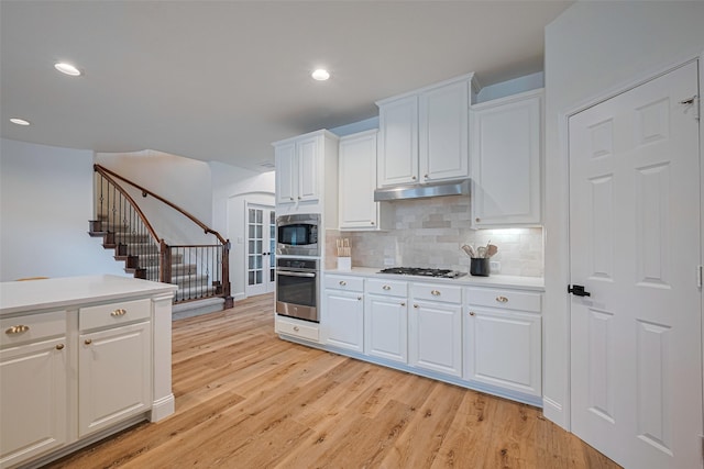 8113 Tranquil Lake Way, Conroe, TX 77385 - kitchen with stainless steel appliances, under cabinet range hood, light countertops, light wood finished floors, and recessed lighting