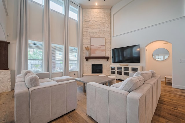 8113 Tranquil Lake Way, Conroe, TX 77385 - living area featuring wood finished floors, a fireplace, a high ceiling, arched walkways, and baseboards