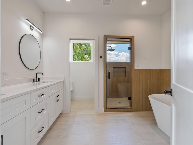 2207 Dan St, Houston, TX 77020 - full bath featuring vanity, a stall shower, a freestanding bath, recessed lighting, and a wainscoted wall
