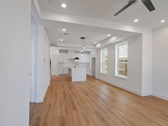 2207 Dan St, Houston, TX 77020 - unfurnished living room with a tray ceiling, ceiling fan, light wood-type flooring, and recessed lighting
