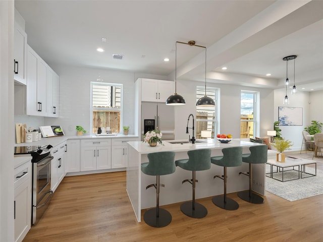 2207 Dan St, Houston, TX 77020 - kitchen featuring stainless steel appliances, light wood-style flooring, recessed lighting, a breakfast bar, and a center island with sink